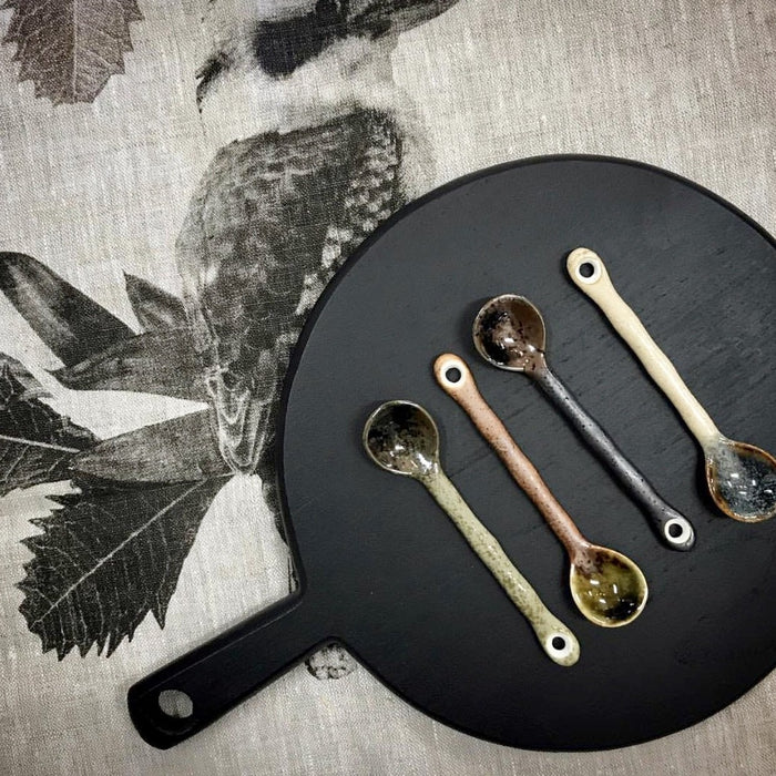black cutting board with set of ceramic tea spoons