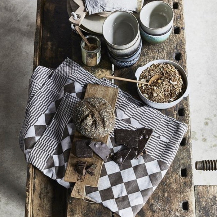 rustic style breakfast table scape with granola, bread, teak wooden servingboards and a brown checkered traditional Dutch cotton tablecloth