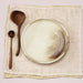 two wooden spoon and a plate in earth tones on a linen napkin