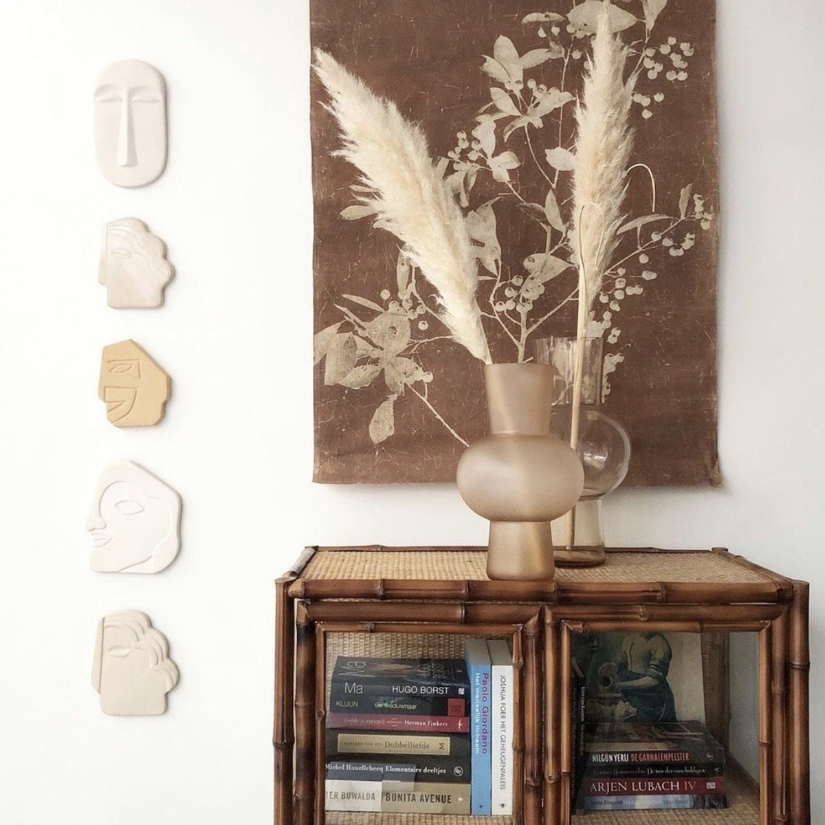 matt vase in peach on a cabinet surrounded by wall decor