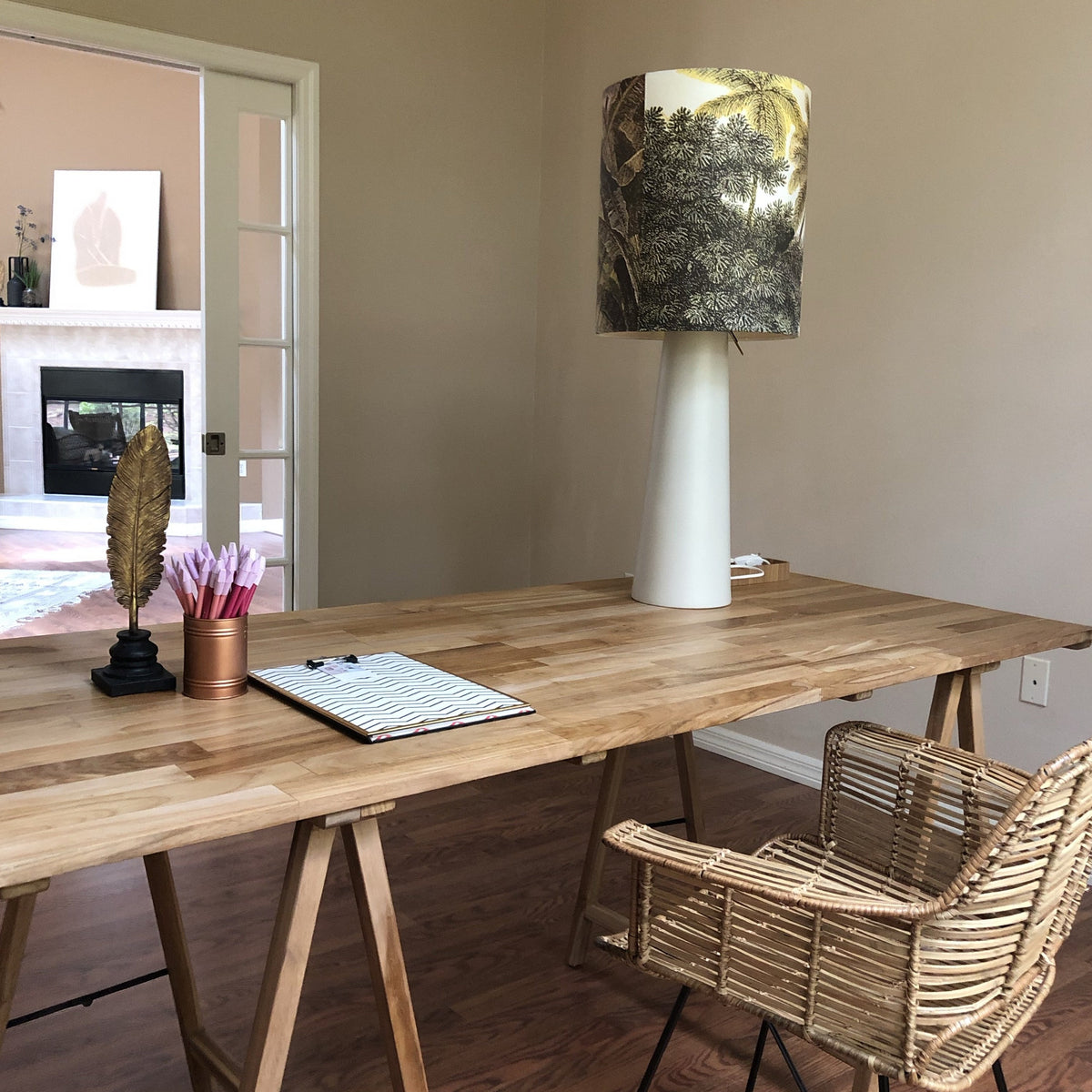 large table lamp with jungle print shade and grey cone shaped base on a desk overlooking den.