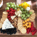 charcuterie plate with crackers, cheese, grapes and tomato's