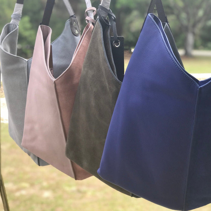 close up of 4 different colored leather bags in grey, pink, green and blue