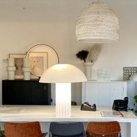 medium size wicker basket light in white above a kitchen island with a white acrylic mushroom table lamp and brass counter stools