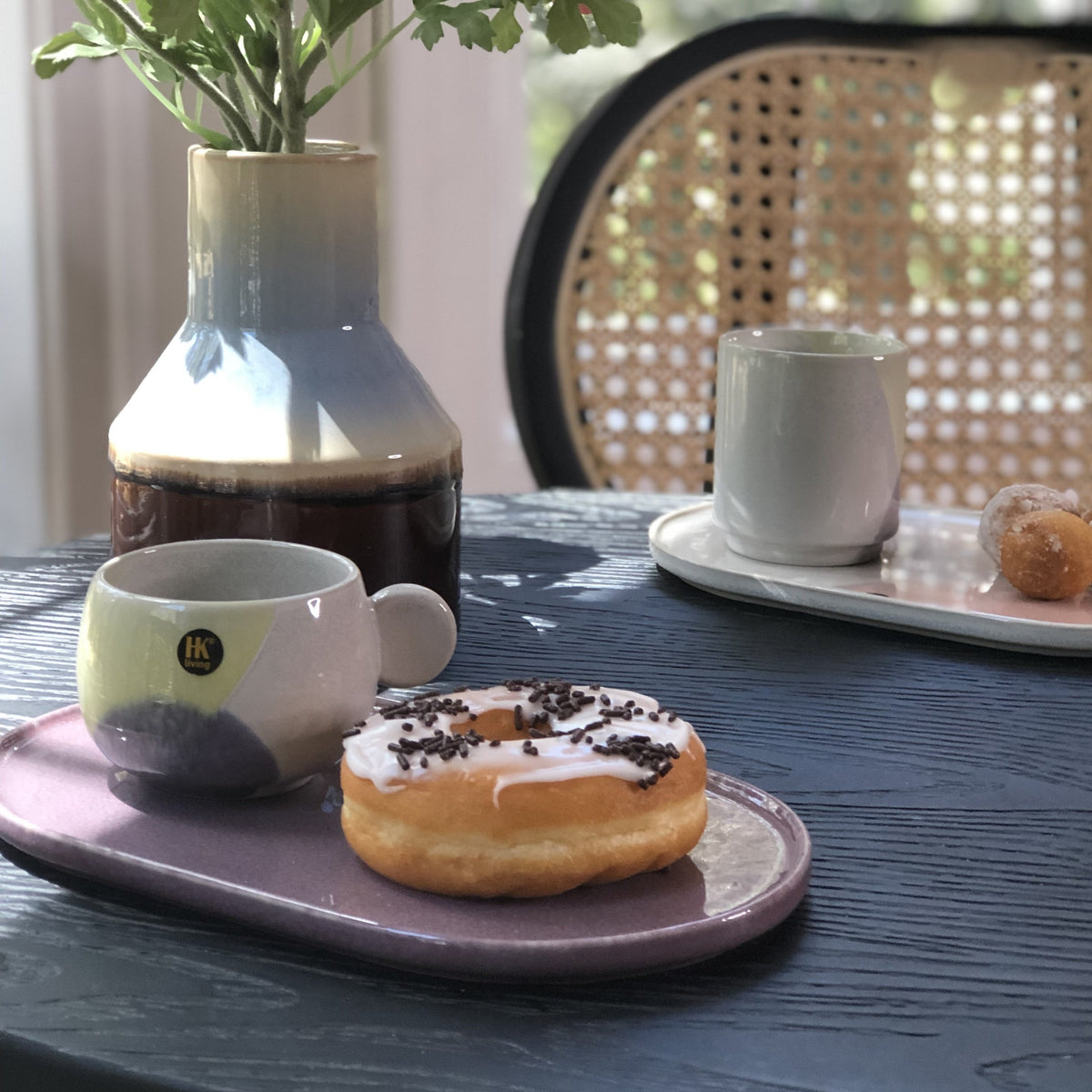 oval plate and coffee cup in pastel colors with donuts on a black table