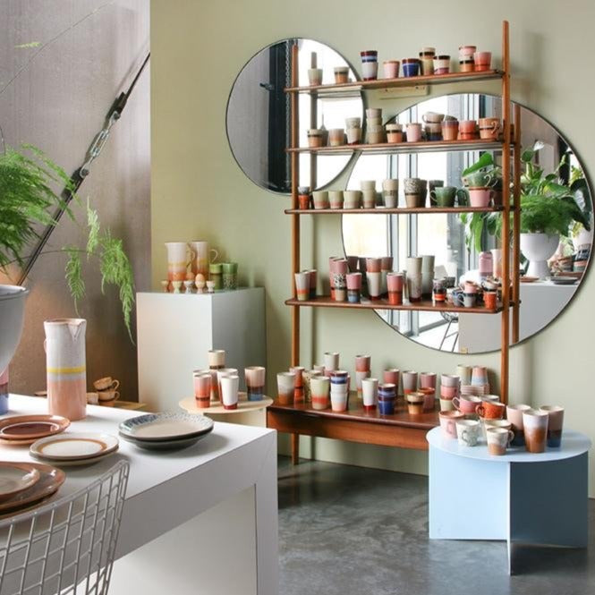 wall with two sizes round mirrors and open shelving with ceramics