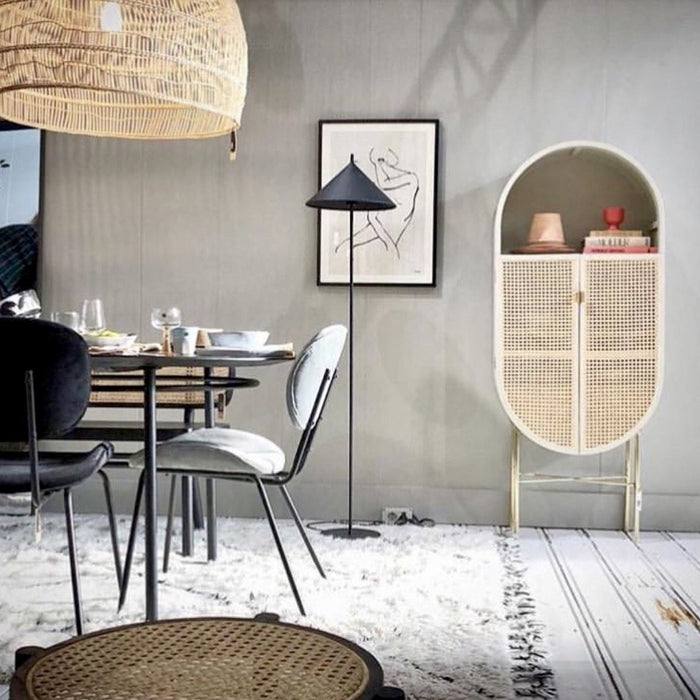 oval shaped cabinet with cane webbing doors in a dining area with a grey wall
