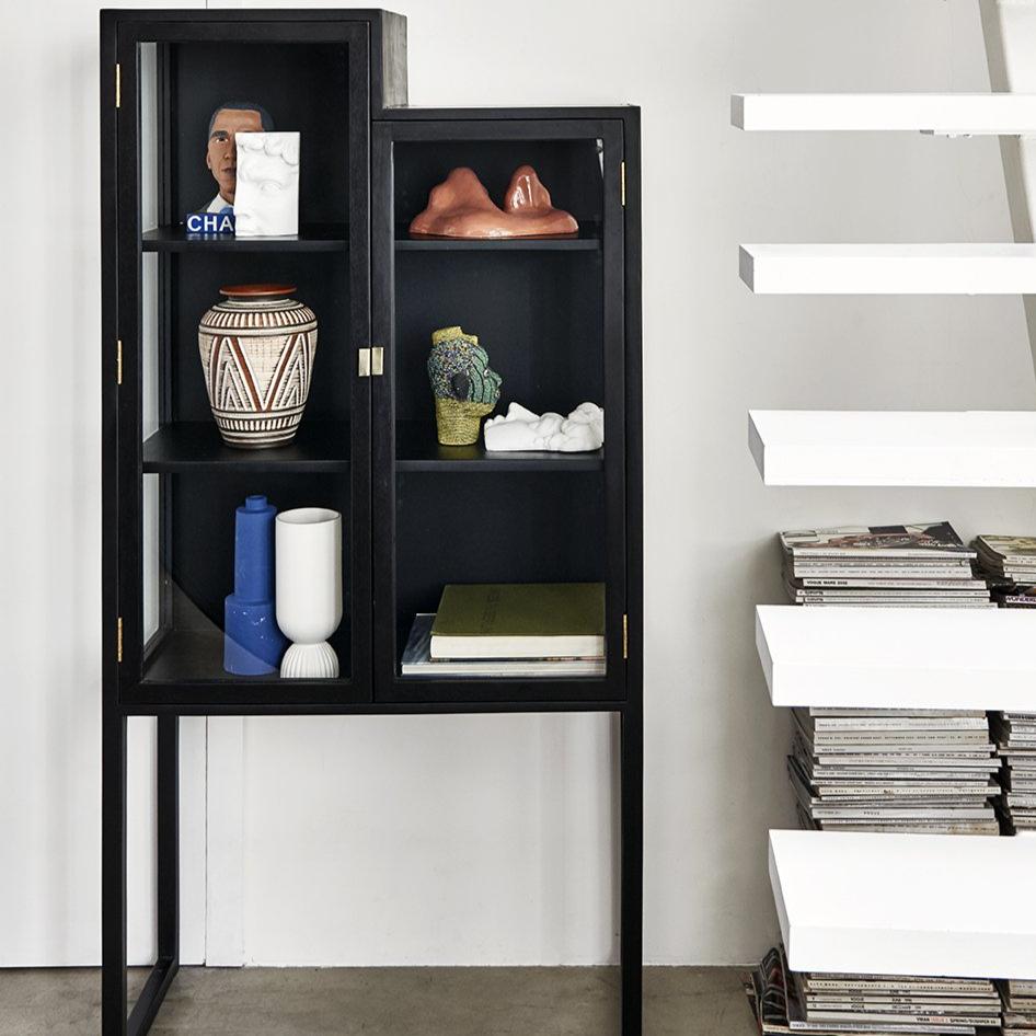 glass and black wood showcase cabinet in staircase shape next to a white staircase